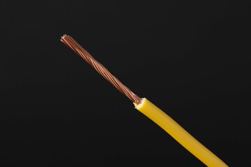 Yellow stripped electrical wire on black background, closeup. Space for text