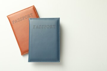 Passports in color covers on light background, top view. Space for text