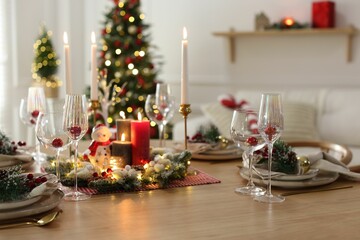 Christmas place setting with festive decor on wooden table in room