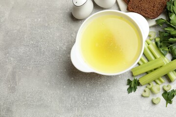 Tasty chicken bouillon served on grey table, flat lay. Space for text