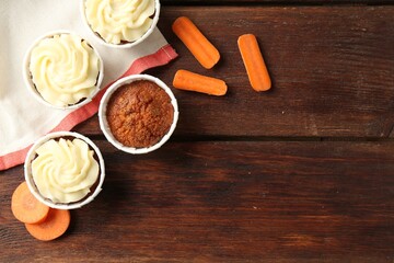 Delicious carrot muffins and fresh vegetables on wooden table, flat lay. Space for text