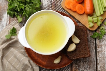 Tasty chicken bouillon served on wooden table, flat lay