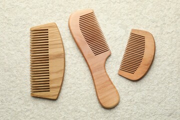 Different wooden hair combs on beige background, top view