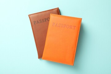 Passports in color covers on light blue background, top view