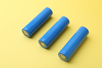 Three AA cell batteries on yellow background, closeup