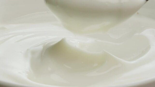 Pouring kefir yogurt into glass cup close-up. Glass with kefir or milk, lactic acid product dairy products concept. Drinking fresh lactose free in morning.