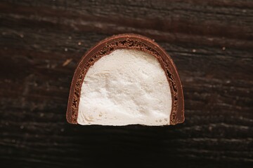 A photo of a piece of chocolate candy with a white, fluffy marshmallow inside