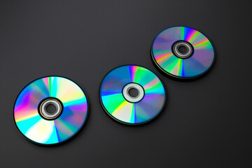 Two cd's with rainbow colored discs on background. Black disk with cd background. Colored disks lying on a black background. A black disk lying on a black background with lifestyle a cd.