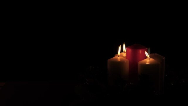Center View of third Sunday in Advent: Advent Wreath With 3 Candles Lit Including Red Candle on Black Background