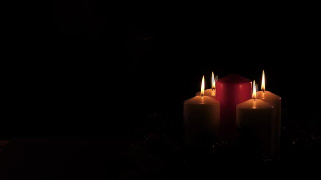 Center View of fourth Sunday in Advent: Advent Wreath With 4 Candles Lit Including Red Candle on Black Background