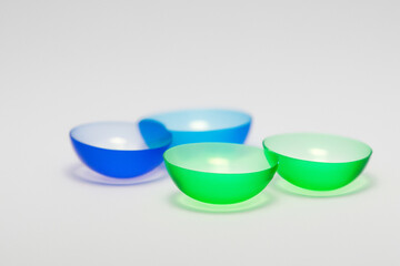 Two colorful bowls sit on white surface. Pair of contact lenses with gray background. Round contact lens lying on a gray background. A woman lying on a gray colored contact lens lifestyle with a gray.