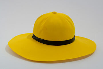 Fototapeta premium Yellow with black band on it. Hat with gray background and yellow hat. A bright yellow hat lies on a gray background in summer. A bright yellow hat lying on a gray background in summer lifestyle.