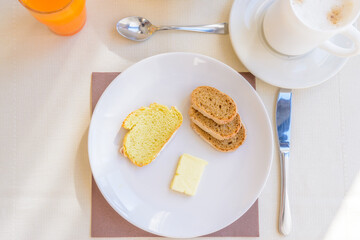 Breakfast including coffee, orange juce, bread, and butter.
