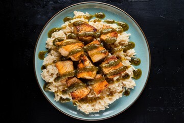 A photo of a plate of spicy chunks of chicken and cooked creamy rice
