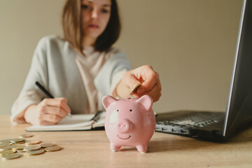 Girl is making calculations, puts savings in a piggy bank.