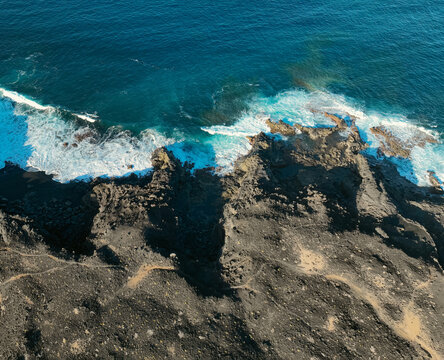 Atlantic ocean with waves and black basalt sand and rocks, view from above from a drone.