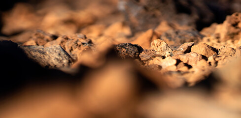 Stones and rocky lava formations on sandy desert terrain closeup.
