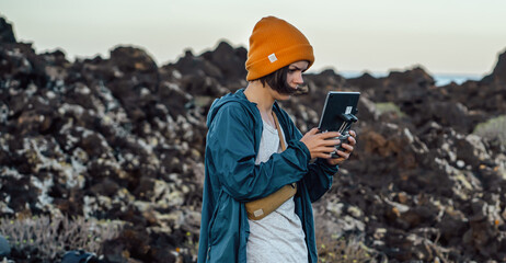 A girl travels and flights a drone, holds a remote control in her hands.