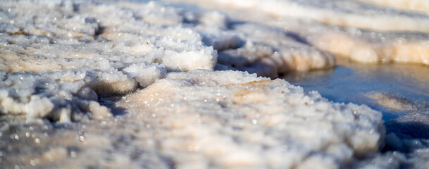 Crystallized white salt on the coast of a Dead sea closeup.