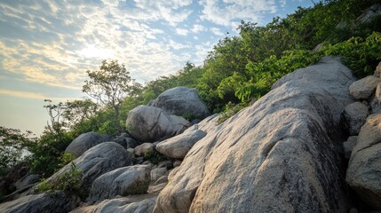 Rocky outcrops rise majestically as the sun begins to rise, illuminating the surrounding greenery and casting a serene glow over the landscape