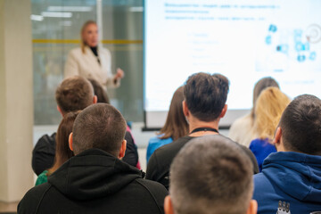 Business seminar with audience focused on presentation by speaker. Engaged attendees in lecture.