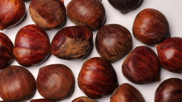 Edible chestnuts (Castanea sativa) rotating in a circle. European sweet chestnuts (marrons), turning. Concept of seasonal food, autumn harvest, and traditional flavors.
