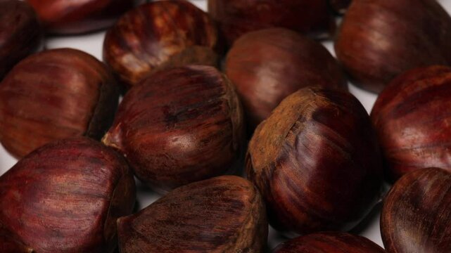 Edible chestnuts (Castanea sativa) rotating in a circle. European sweet chestnuts (marrons), turning. Concept of seasonal food, autumn harvest, and traditional flavors.