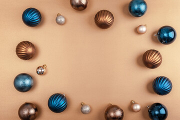 Christmas ornaments in blue, bronze, and silver arranged on a gold background. Flat lay, copy space