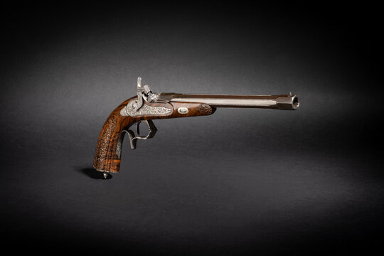 Studioaufnahme einer historischen Perkussion Scheibenpistole Pistole Kurzwaffe auf schwarzem Untergrund mit Schlagschatten dramatischen Licht
