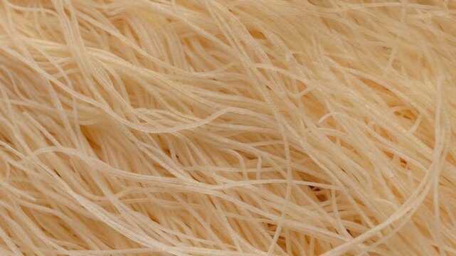 Kataifi dough in smooth motion. Delicate, raw thin strands of dough used for making trendy and gourmet desserts.