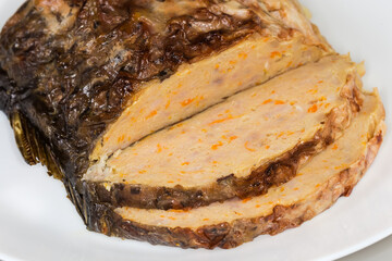 Partly sliced stuffed carp piece on dish, close-up