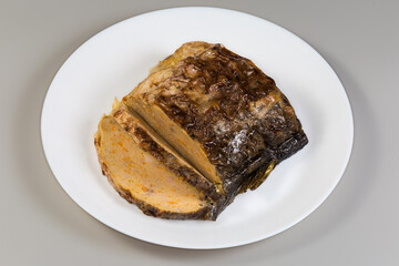 Partly sliced piece of stuffed fish carp on white dish