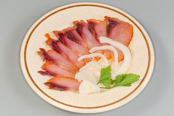 Sliced cold smoked freshwater fish with fresh onion on saucer