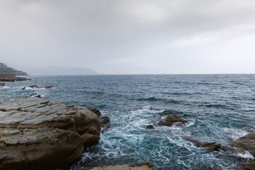Stone shore of sea against the sky in overcast rainy day