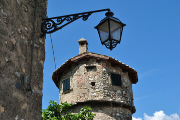 Old Cast Iron Lantern and Stone Tower in Close Up on Sunny Italian Day with Blue Sky