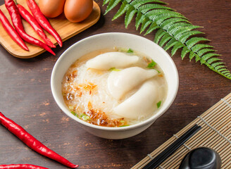 Dumplings Rice Noodles Soup served in bowl with chopsticks and spoon isolated on wooden table side view of Taiwan food