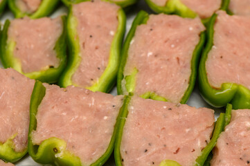 Delicious stuffed green peppers filled with seasoned meat preparing for baking