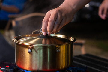 A brass pot is placed on a picnic stove for boiling soup.