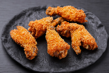 Fried chicken wings on black. Plate of wings with a black sauce on it. A plate of fast food wings lies on a black plate. Fast food lies on a plate with lifestyle breading wings.