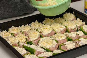 Deliciously preparing stuffed peppers topped with creamy cheese in a cozy kitchen