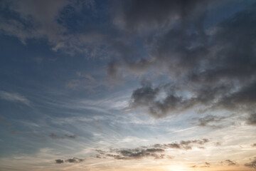 Obraz premium Sky and clouds for a background for a photo, featuring vibrant orange and yellow tones. Wispy clouds stretch across the sky, creating a peaceful, atmospheric composition perfect for nature, travel.