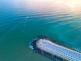 Sakarya High-angle, full shot of a tranquil coastal scene. Aerial View of Coastal Breakwater with Small Boat on Calm Turquoise Water. Karasu Adapazari Turkiye Drone Shot Turkey Holiday travel photo 