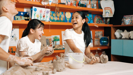Caucasian highschool girl modeling cup of clay while looking smart boy in art class at workshop. Multicultural student playing or making cup of clay art in creative activity. Education. Edification.