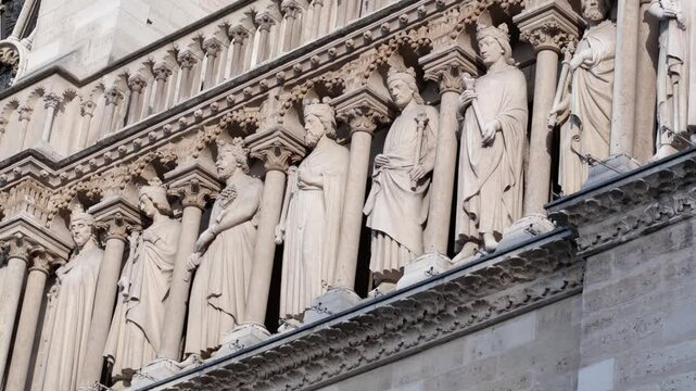 Intricate stone carvings of saints on the facade of Notre Dame Cathedral in Paris, showcasing Gothic architecture and religious art