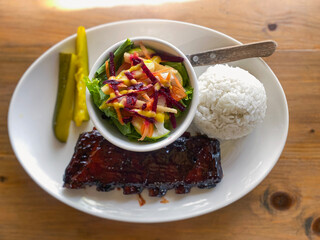 caramelized fried BBQ beef ribs with vegetable salad, rice and pickled cucumbers