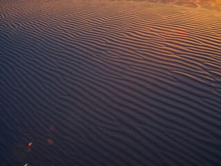 Twilight casts a subtle light over rippling desert sand dunes, creating a serene and mystical atmosphere. Ideal for themes of nature, tranquility, and the beauty of landscapes. Perfect for promotional