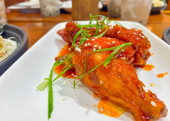 fried chicken in sweet and sour sauce with sesame seeds and fresh herbs in a restaurant