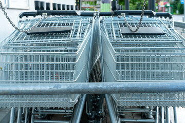 Closse up of two rows of shopping carts in a stand at a supermarket, waiting for customers willing...