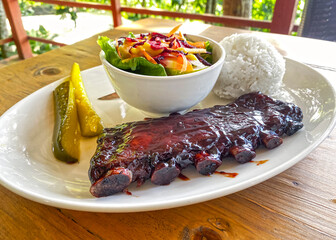 caramelized fried BBQ beef ribs with vegetable salad, rice and pickled cucumbers