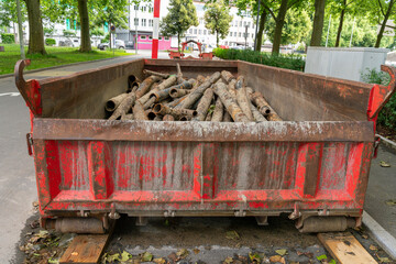 Old red container on a construction  site with old metal tubes collected for recycling during the process of the renewal of the water and sewer system.